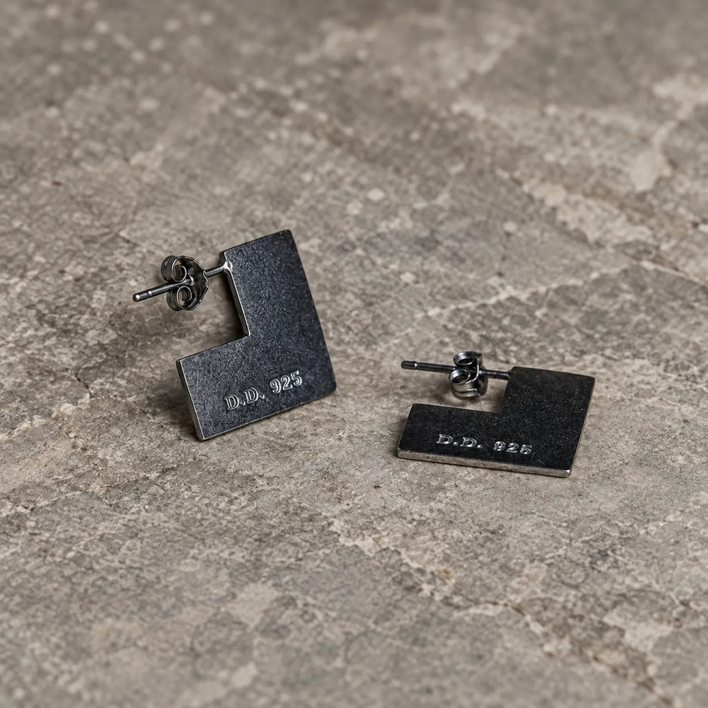 Back view of broken square stud earrings showing their posts, butterfly backs and sterling silver marks