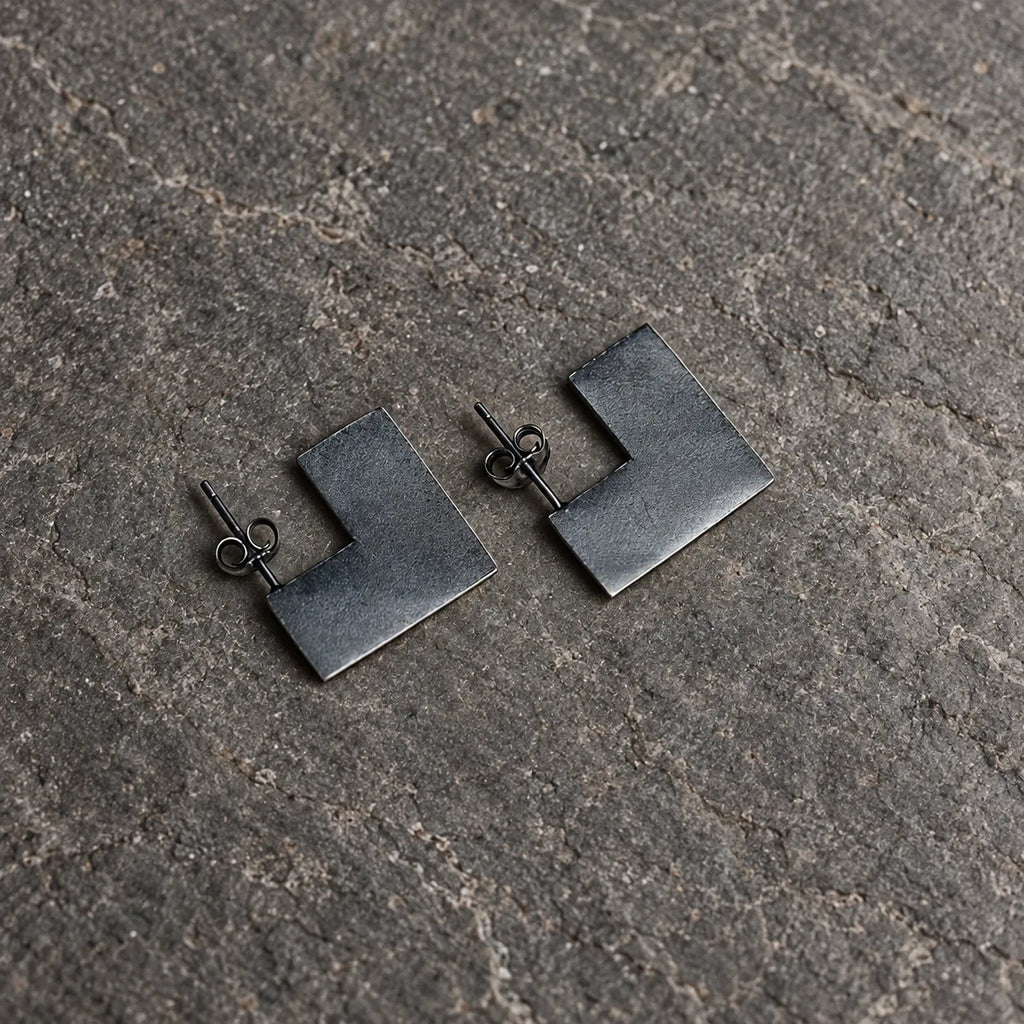 Angled view of open square stud earrings showing their flat surfaces and straight posts