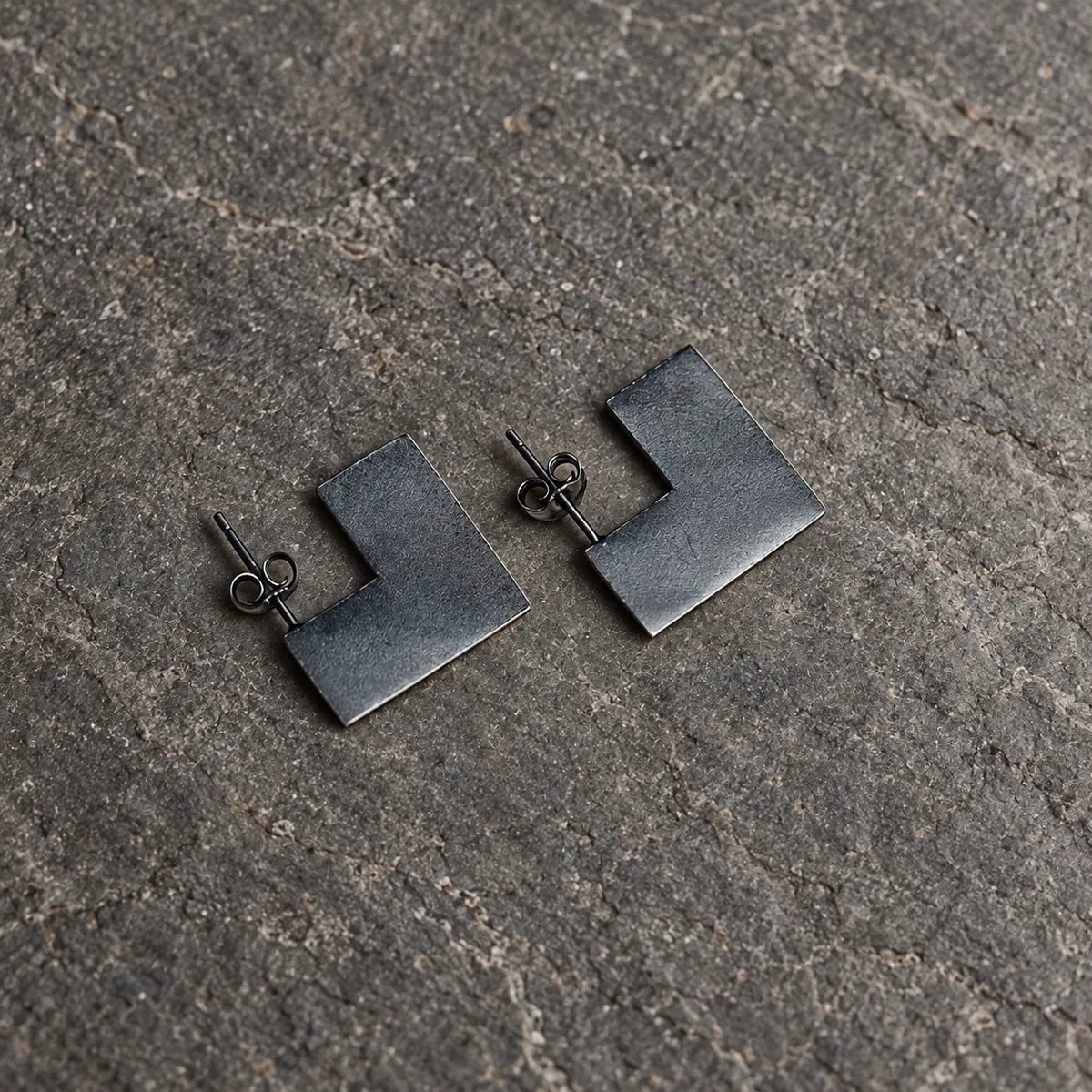 Angled view of open square stud earrings showing their flat surfaces and straight posts