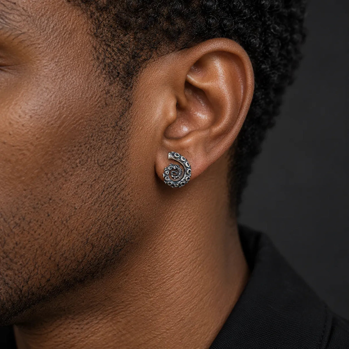 Coiled tentacle stud earring worn to show its approximate 10 by 13 mm size