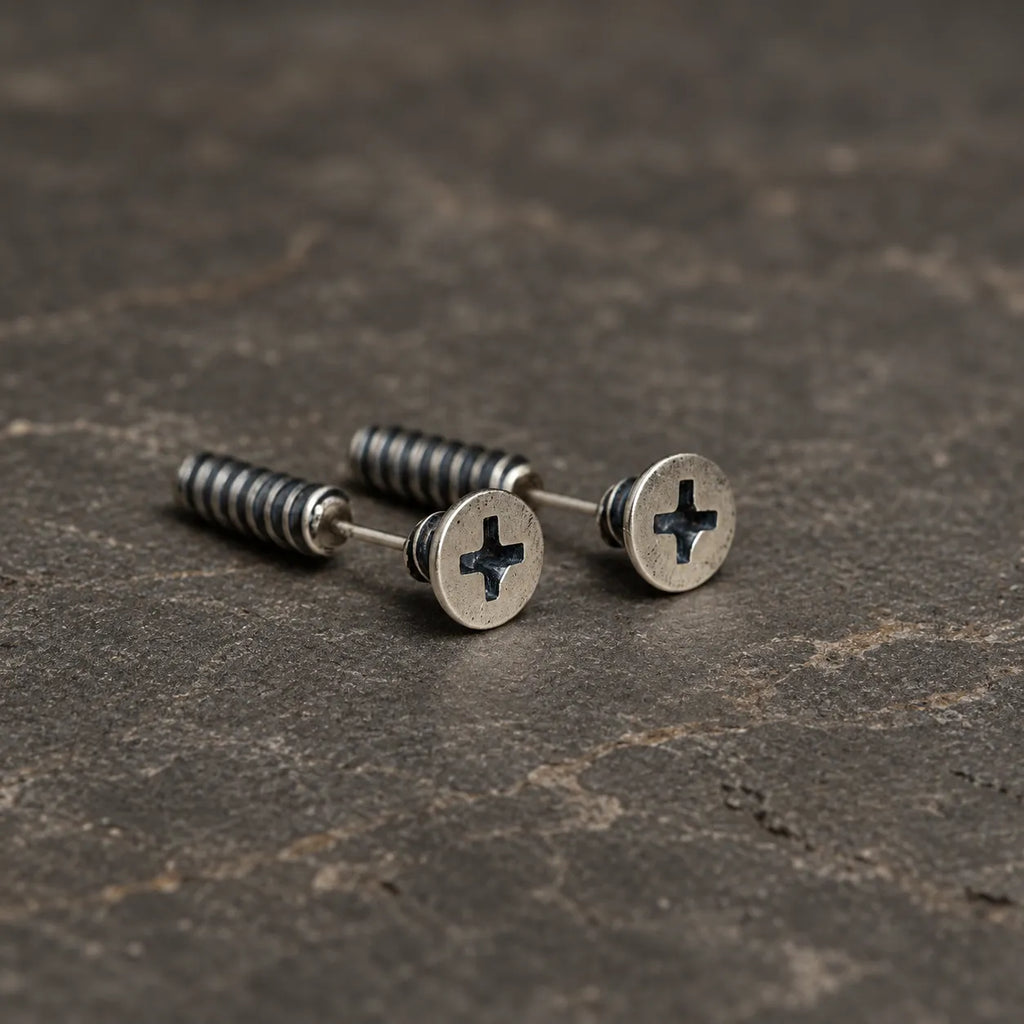 Pair of oxidized sterling silver cross-slot screw stud earrings on dark stone