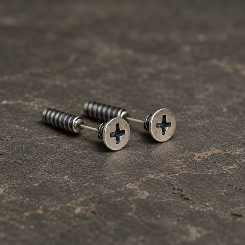 Pair of oxidized sterling silver cross-slot screw stud earrings on dark stone