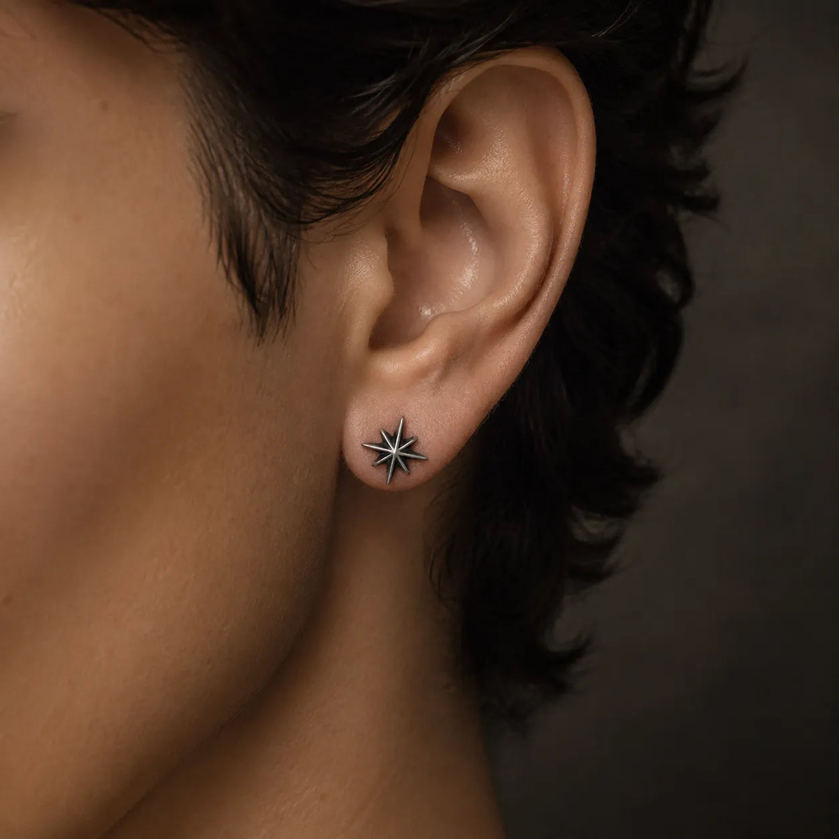 Small eight-point starburst stud earring worn on an ear to show its 10 mm size