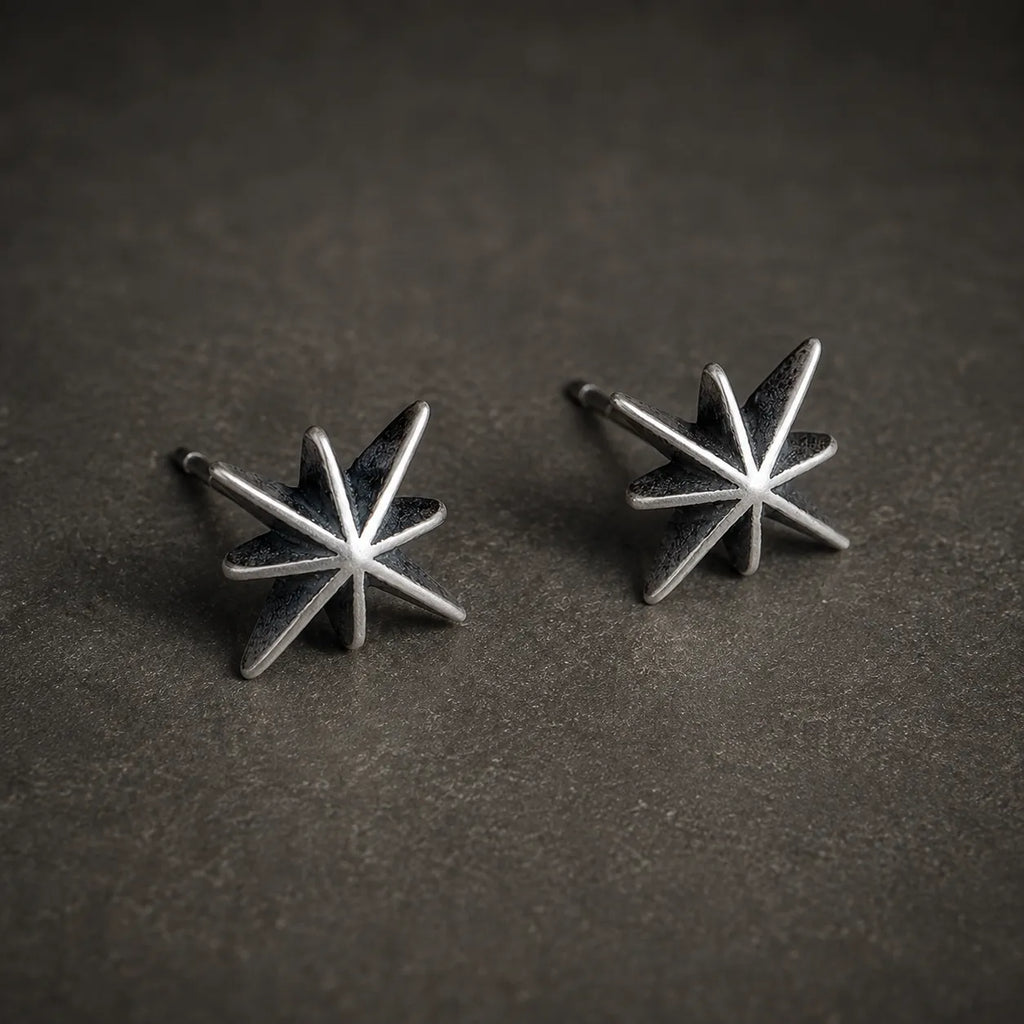 Angled view of oxidized silver starburst stud earrings showing their raised design and posts