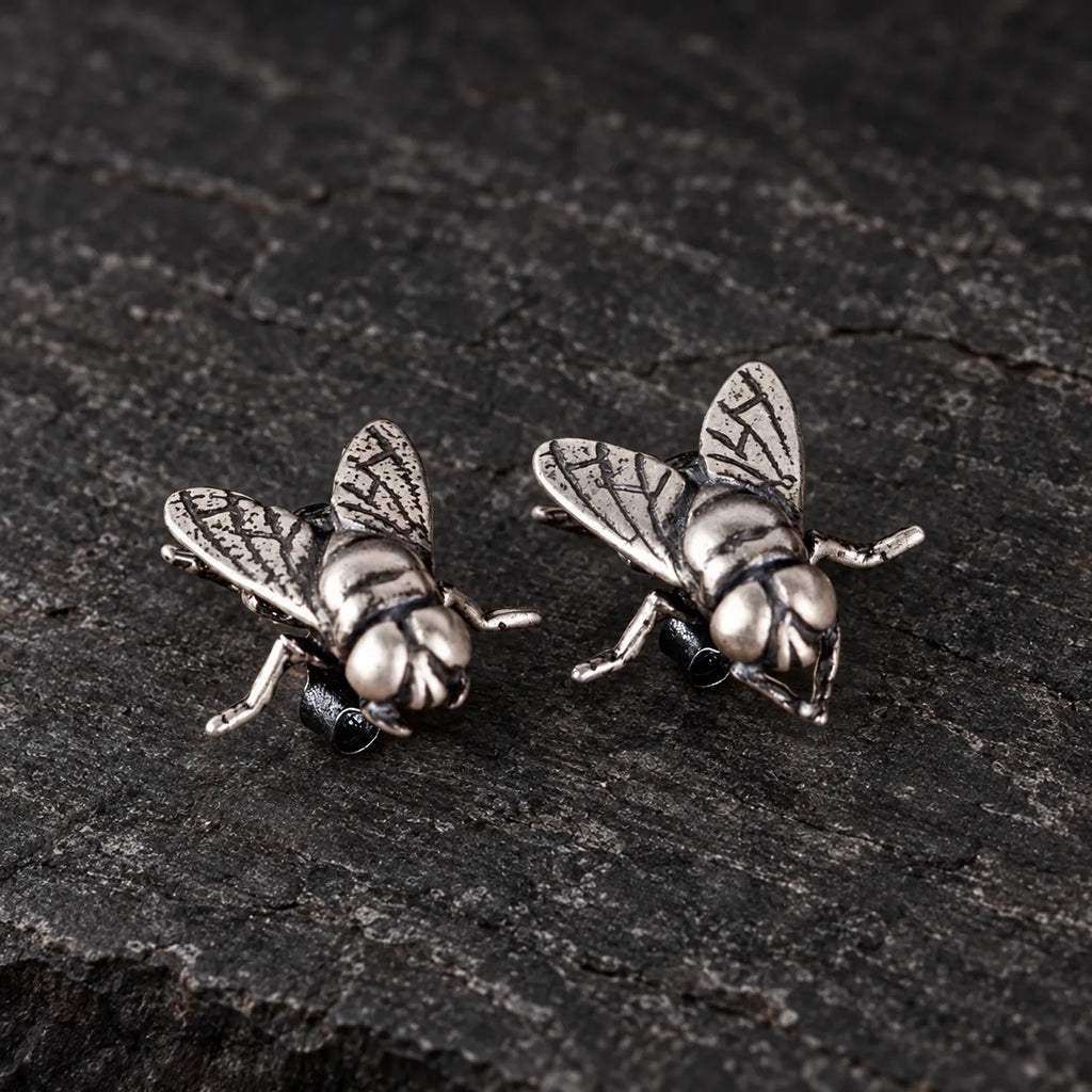 Three-quarter view of sculpted fly stud earrings showing their wings and posts