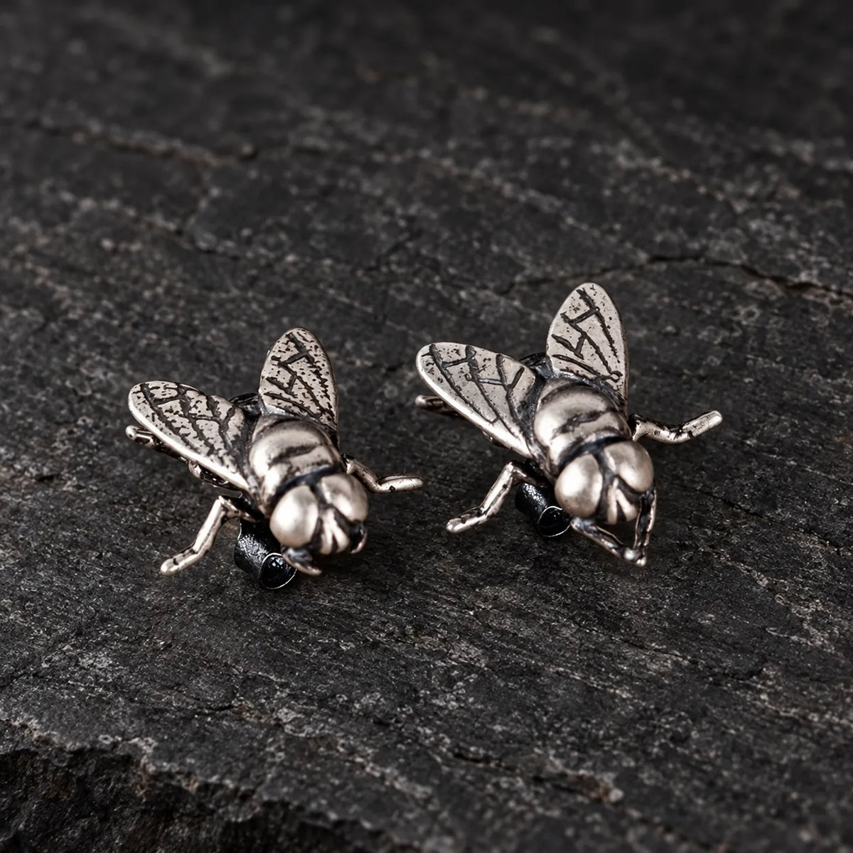 Three-quarter view of sculpted fly stud earrings showing their wings and posts