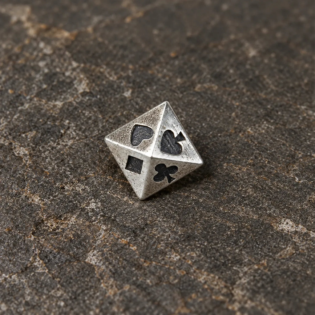 Close-up of a silver pyramid stud engraved with spade heart club and diamond symbols