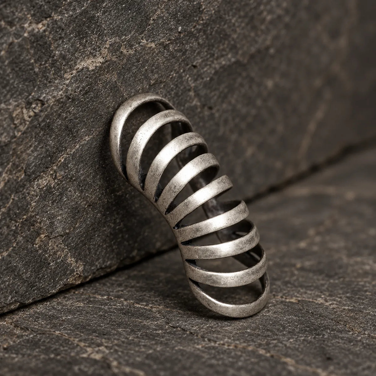 Upright view of a gothic rib ear cuff leaning against dark stone