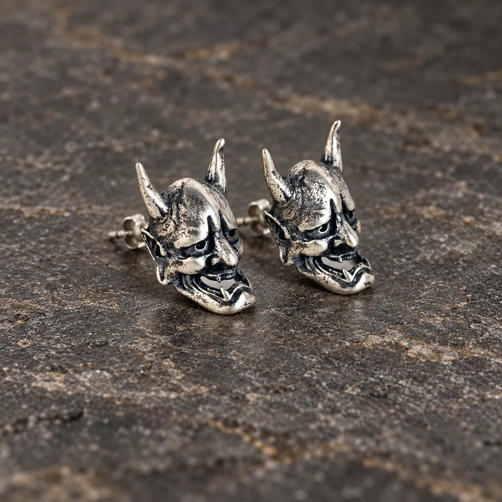 Angled view of oxidized silver Hannya mask stud earrings with visible posts and backs