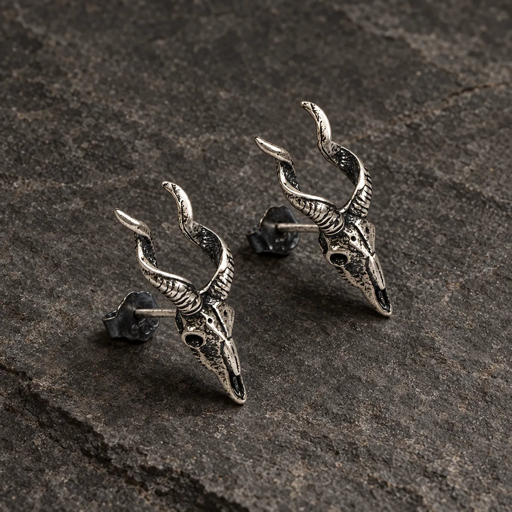 Angled view of horned skull stud earrings showing their sculpted depth and posts