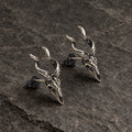 Angled view of horned skull stud earrings showing their sculpted depth and posts