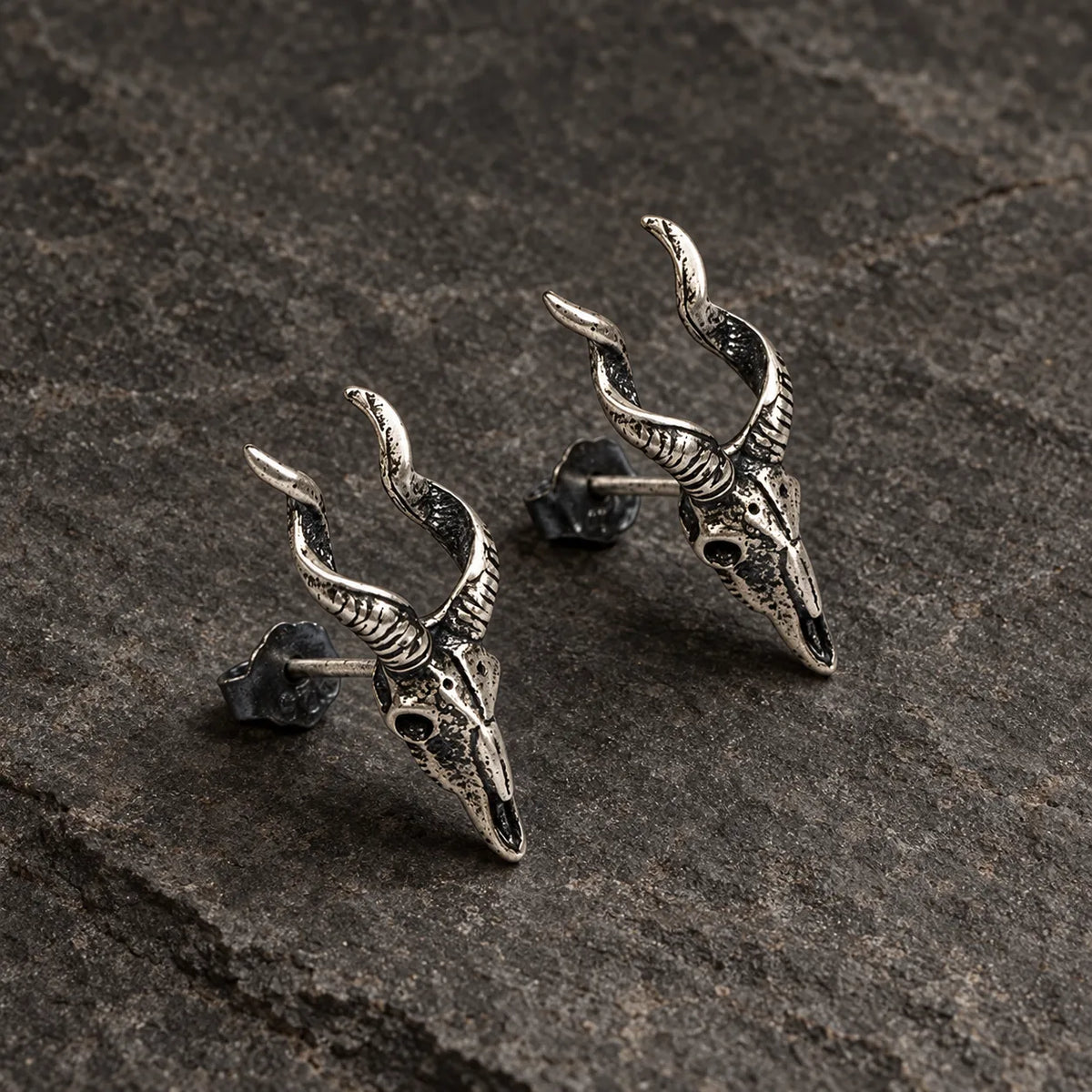 Angled view of horned skull stud earrings showing their sculpted depth and posts