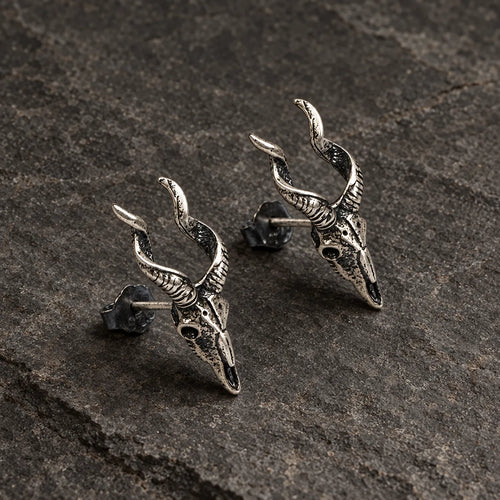 Angled view of horned skull stud earrings showing their sculpted depth and posts
