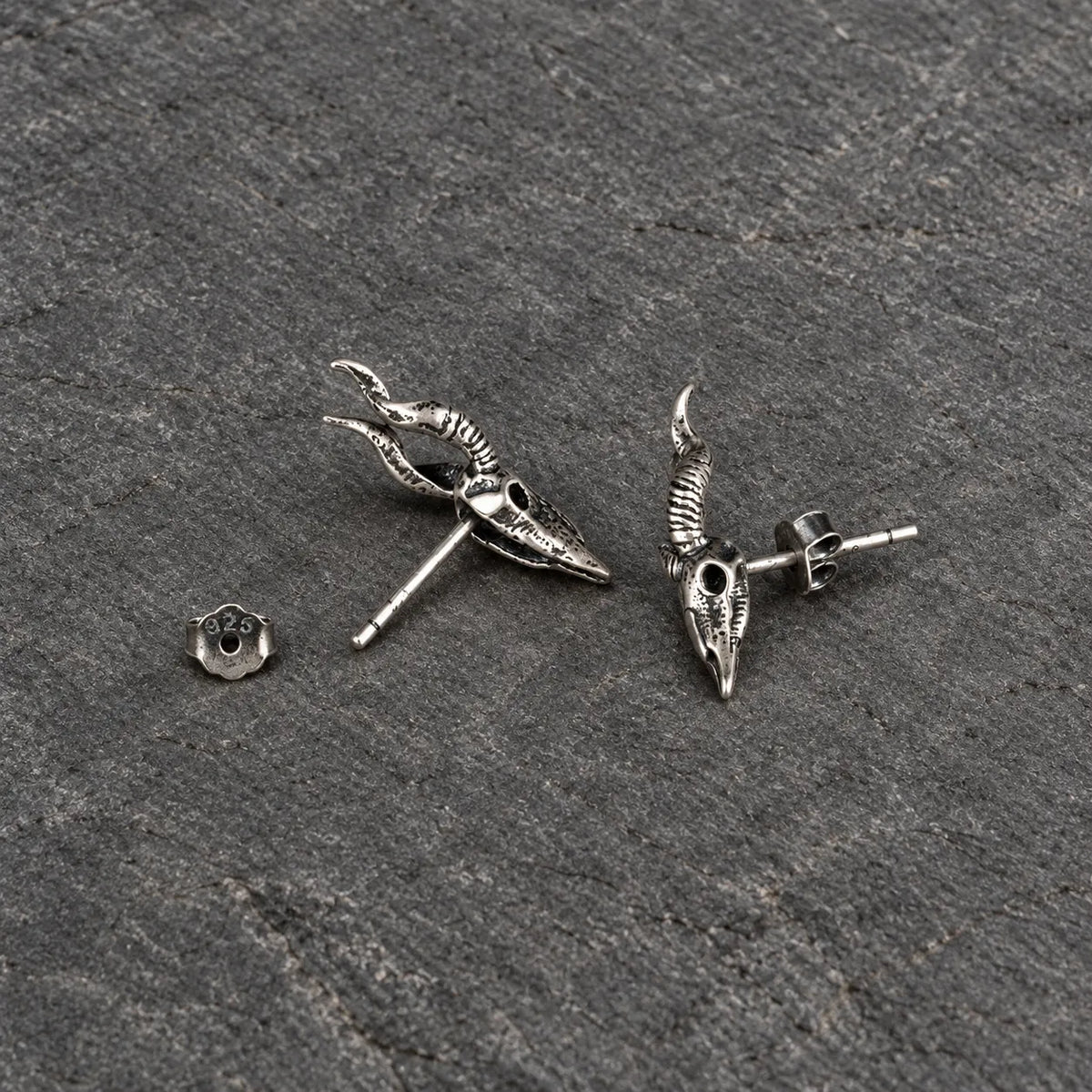 Back and side view of horned skull stud earrings with straight posts and butterfly backs