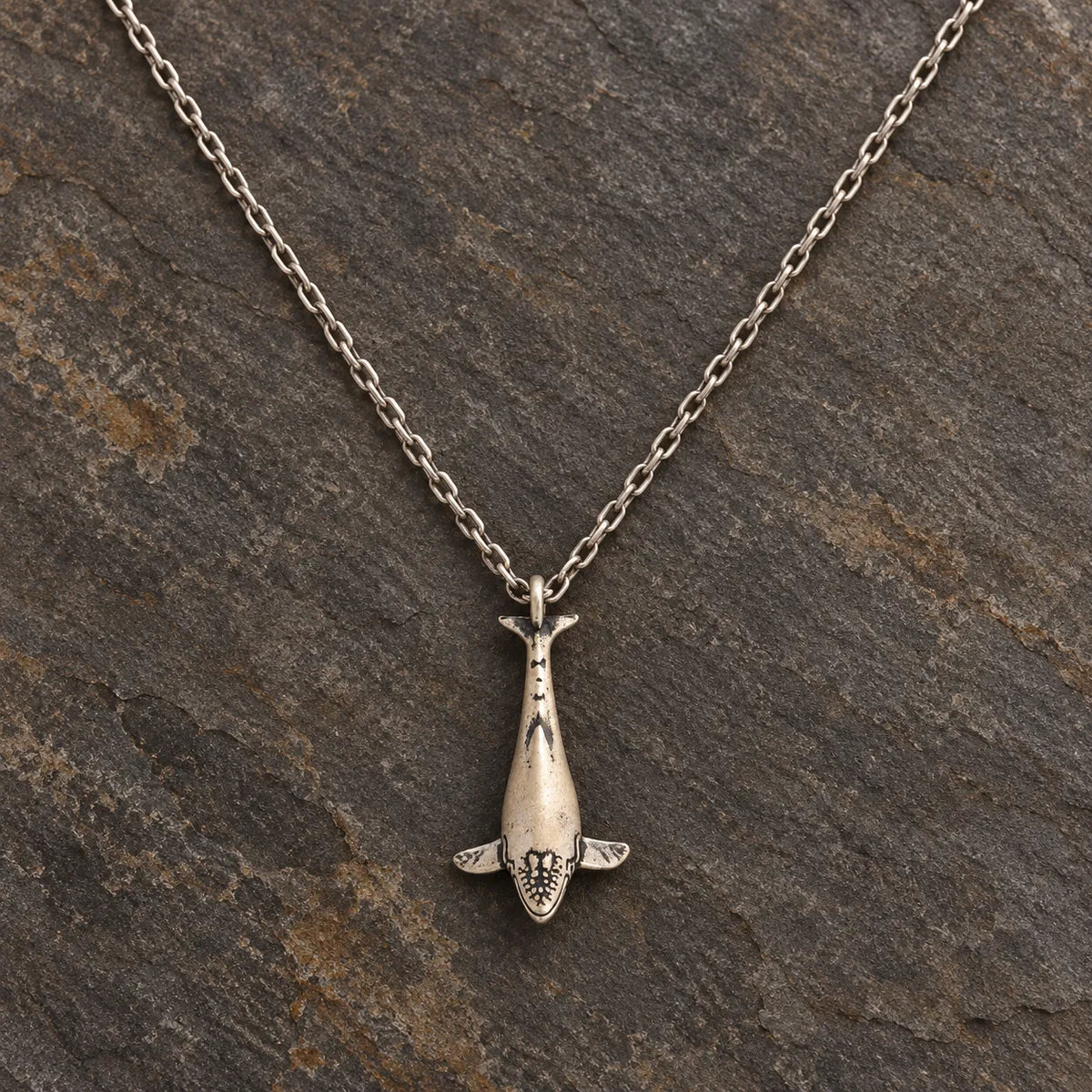 Front view of a sterling silver humpback whale pendant shown with an optional 1.5 mm chain