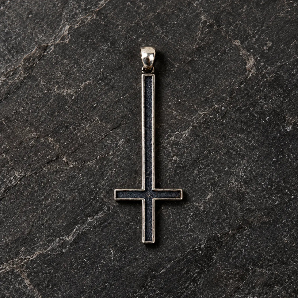 Front view of an oxidized 925 sterling silver inverted cross pendant on dark stone