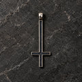 Front view of an oxidized 925 sterling silver inverted cross pendant on dark stone