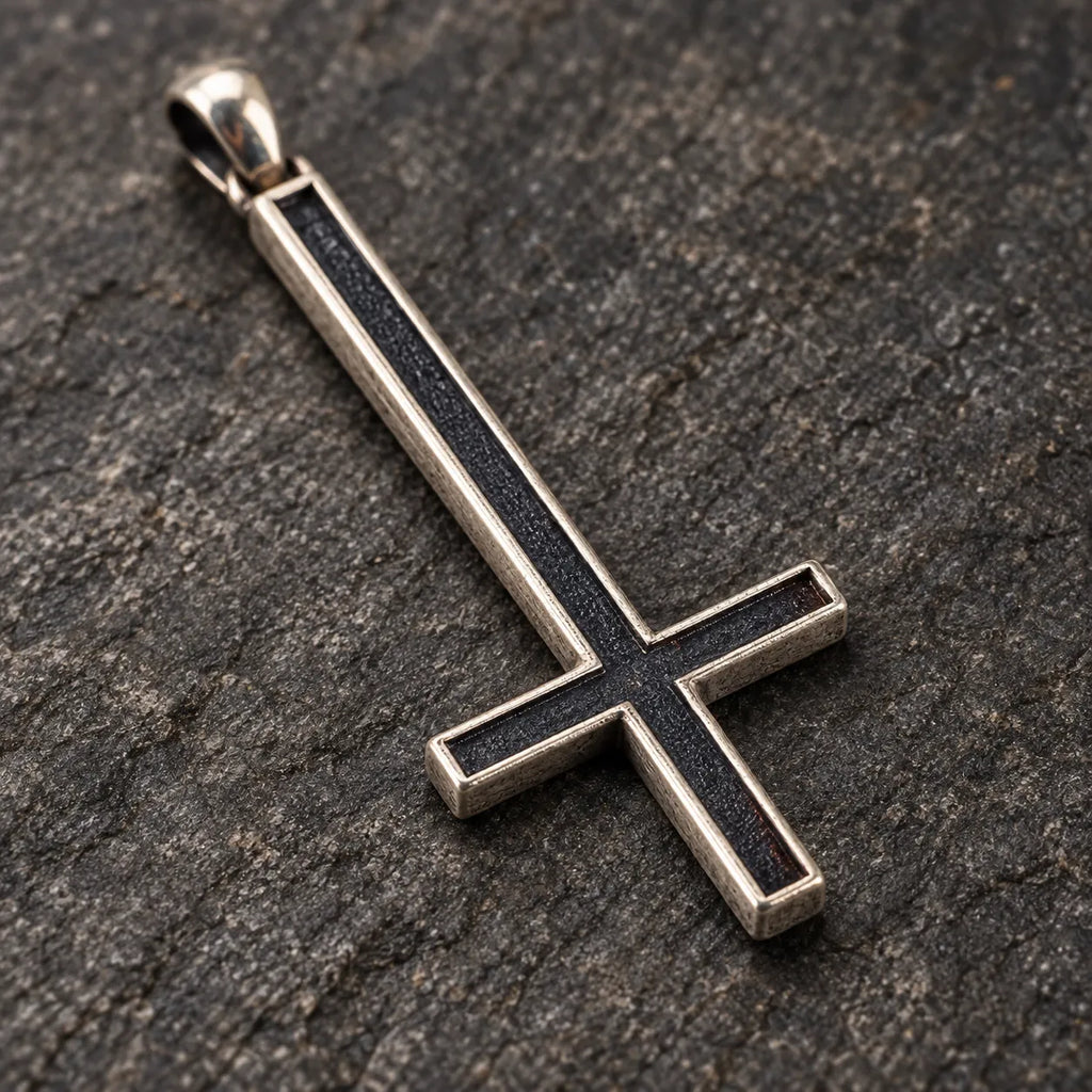 Close-up of the dark oxidized center and raised silver border of an inverted cross pendant