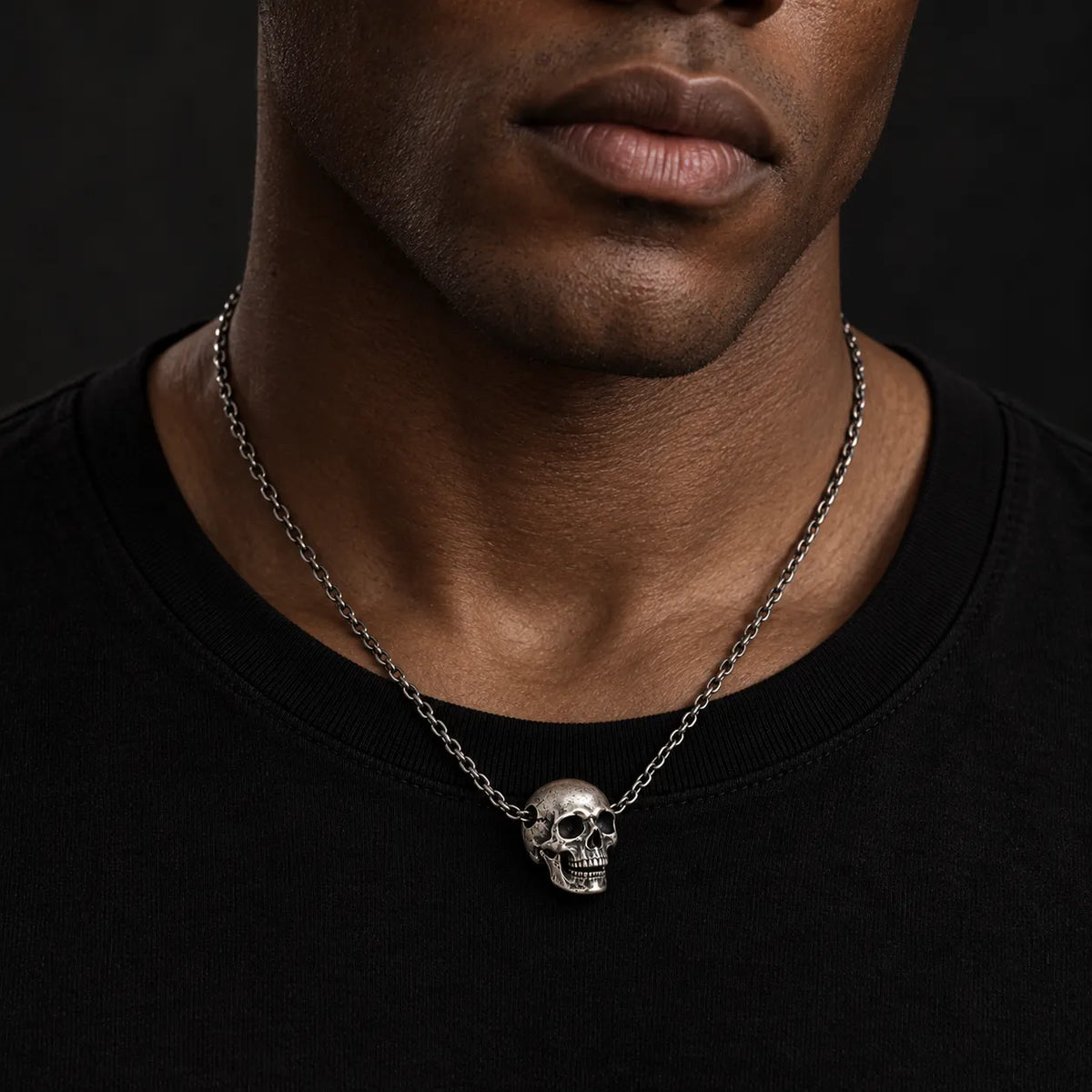 Black male model wearing the No. 6 articulated skull pendant at its actual 18 by 20 mm size on a 3.0 mm chain