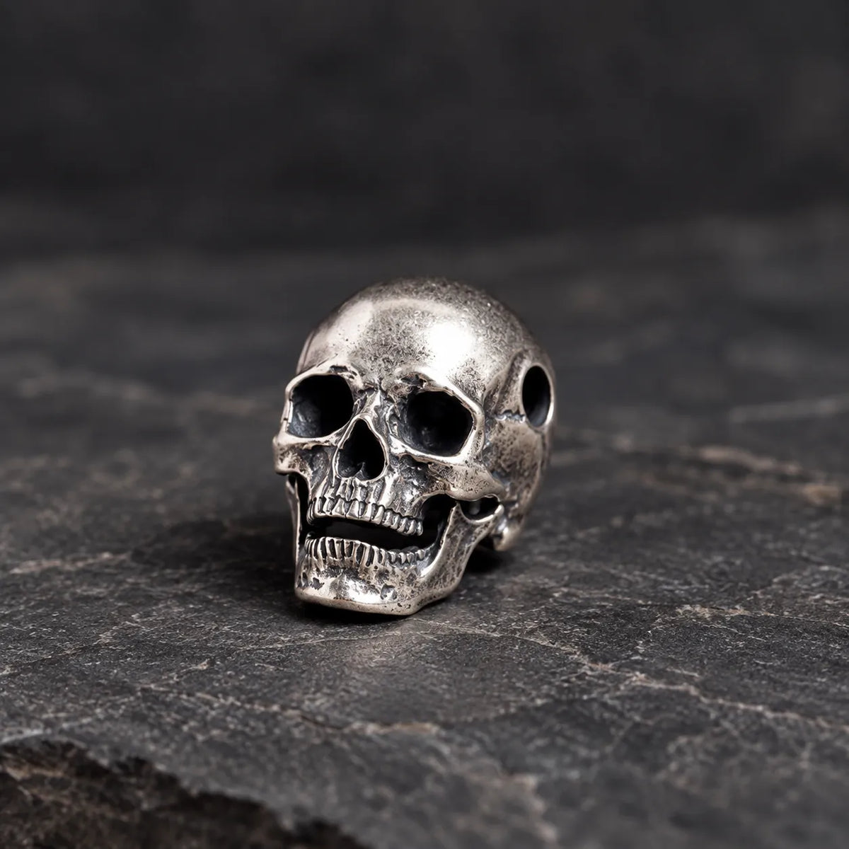 Front three-quarter view of the No. 6 articulated silver skull pendant with its jaw slightly open