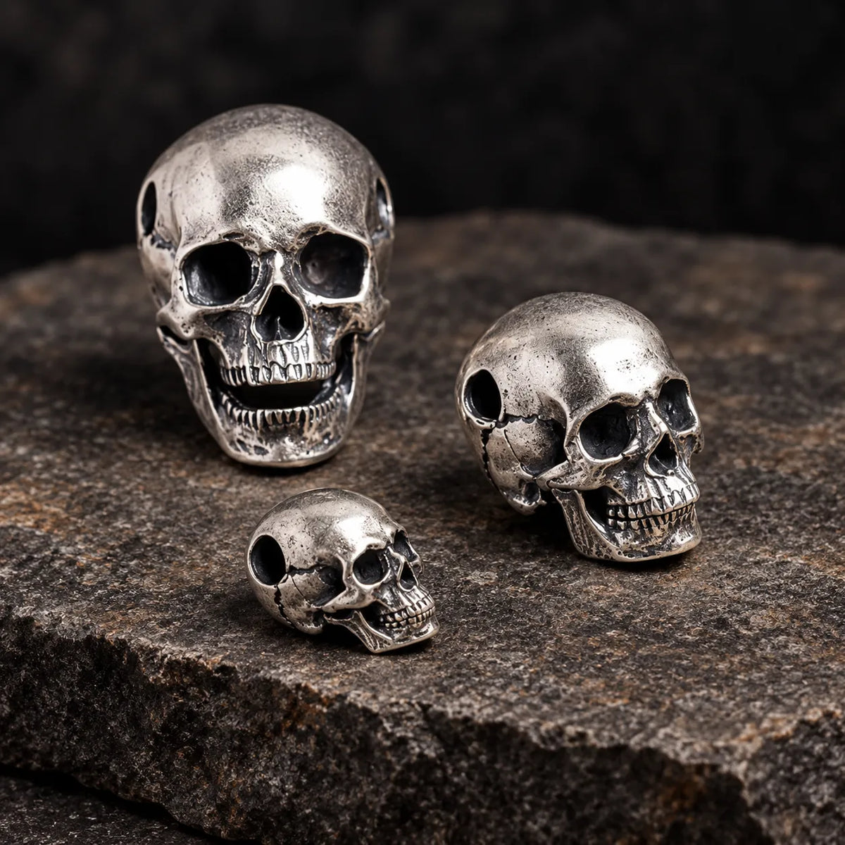 Three larger articulated skull pendant sizes shown from front, three-quarter and side angles