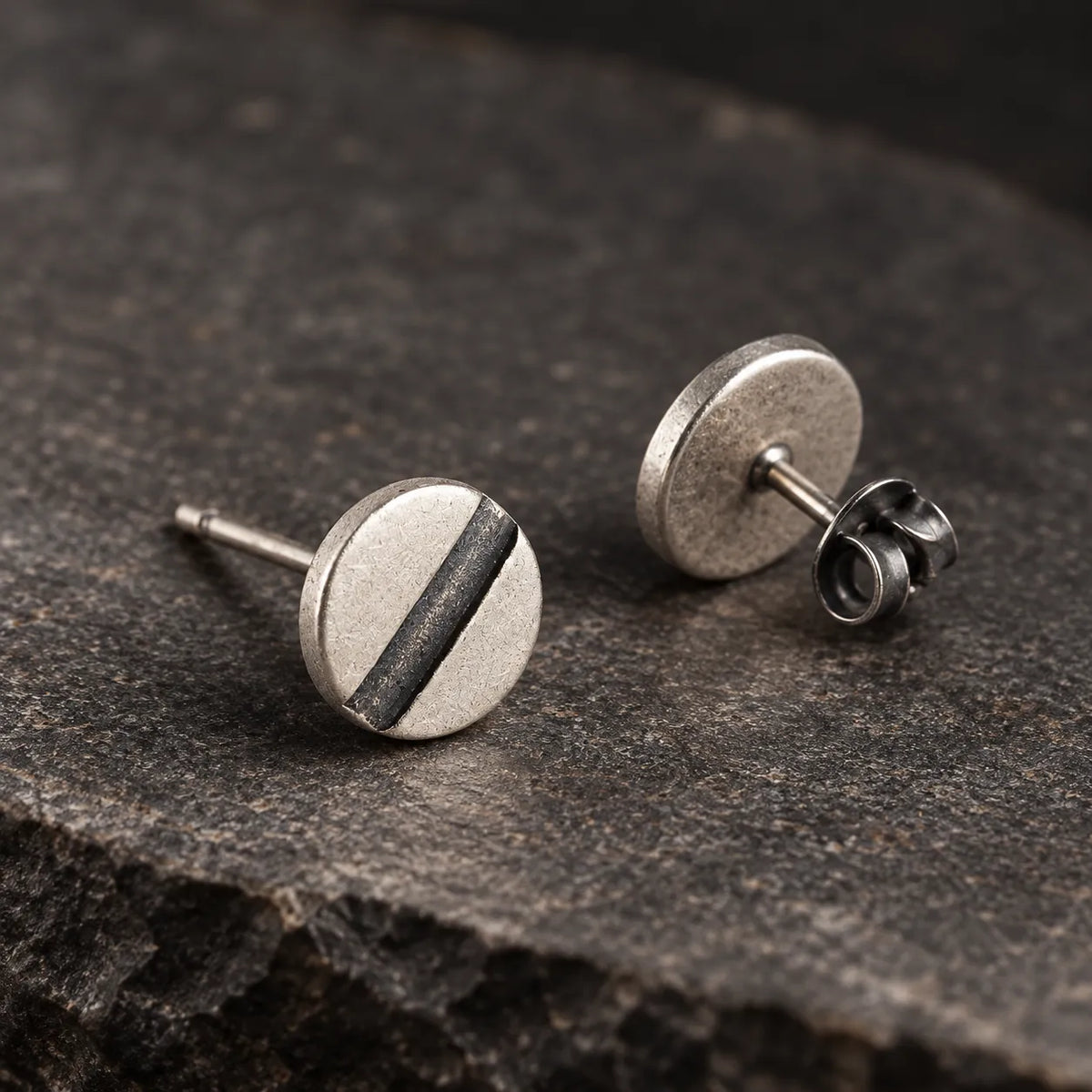 Angled view of round line disc earrings showing their straight posts and butterfly backs