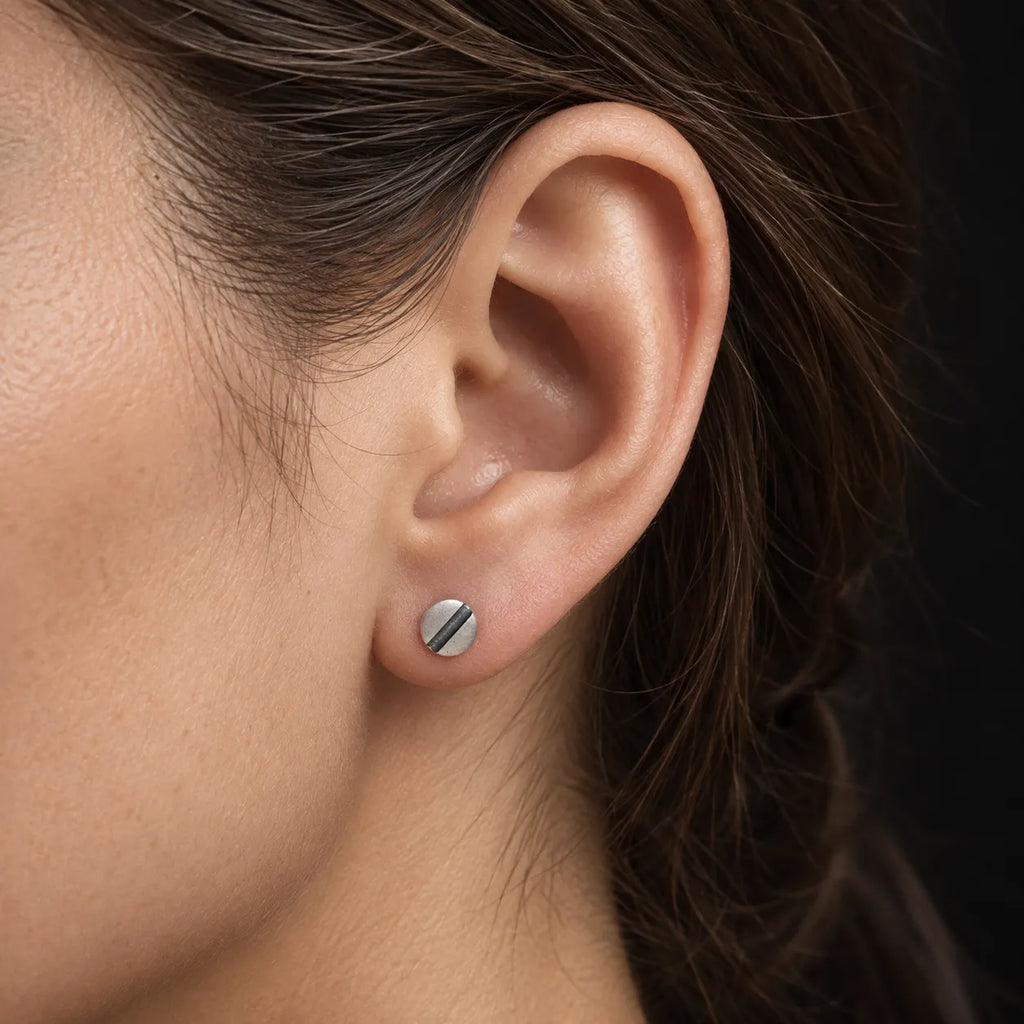 Close-up of a woman wearing a small 6 mm oxidized line disc stud earring