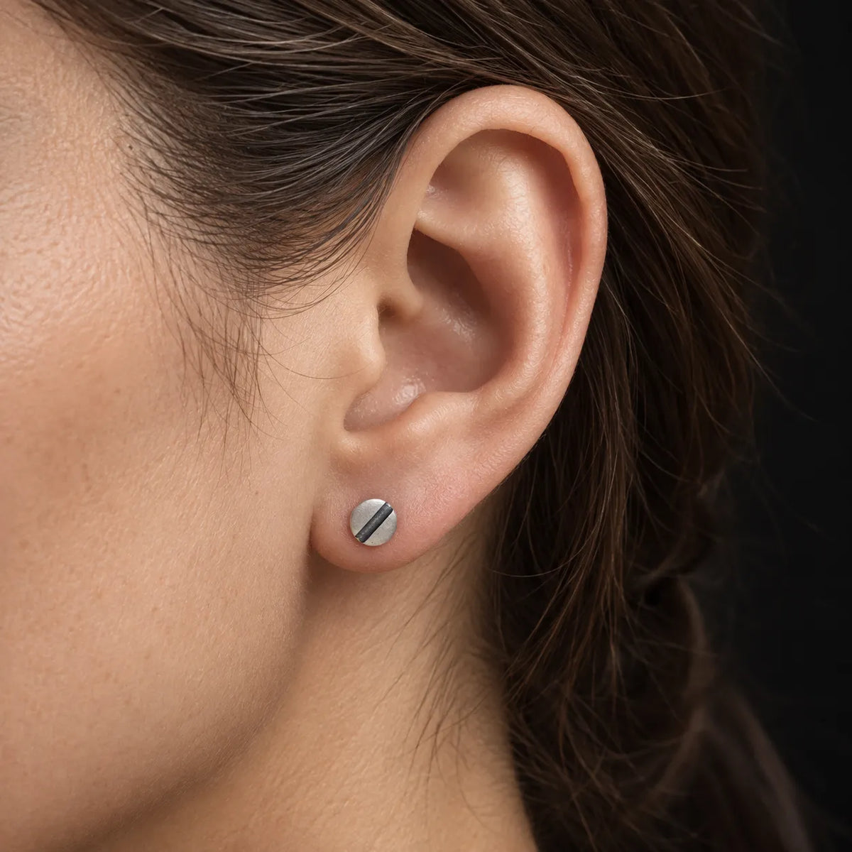 Close-up of a woman wearing a small 6 mm oxidized line disc stud earring