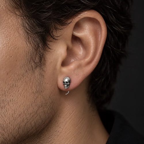 Mini skull hook earring worn on an ear to show its approximately 8 mm height