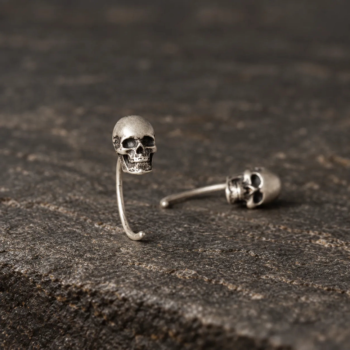 Mini skull earrings shown upright and lying flat to display their curved wire structure