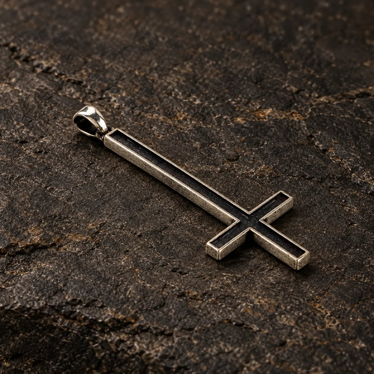 Three-quarter view of an oxidized silver inverted cross pendant showing its recessed face and thickness