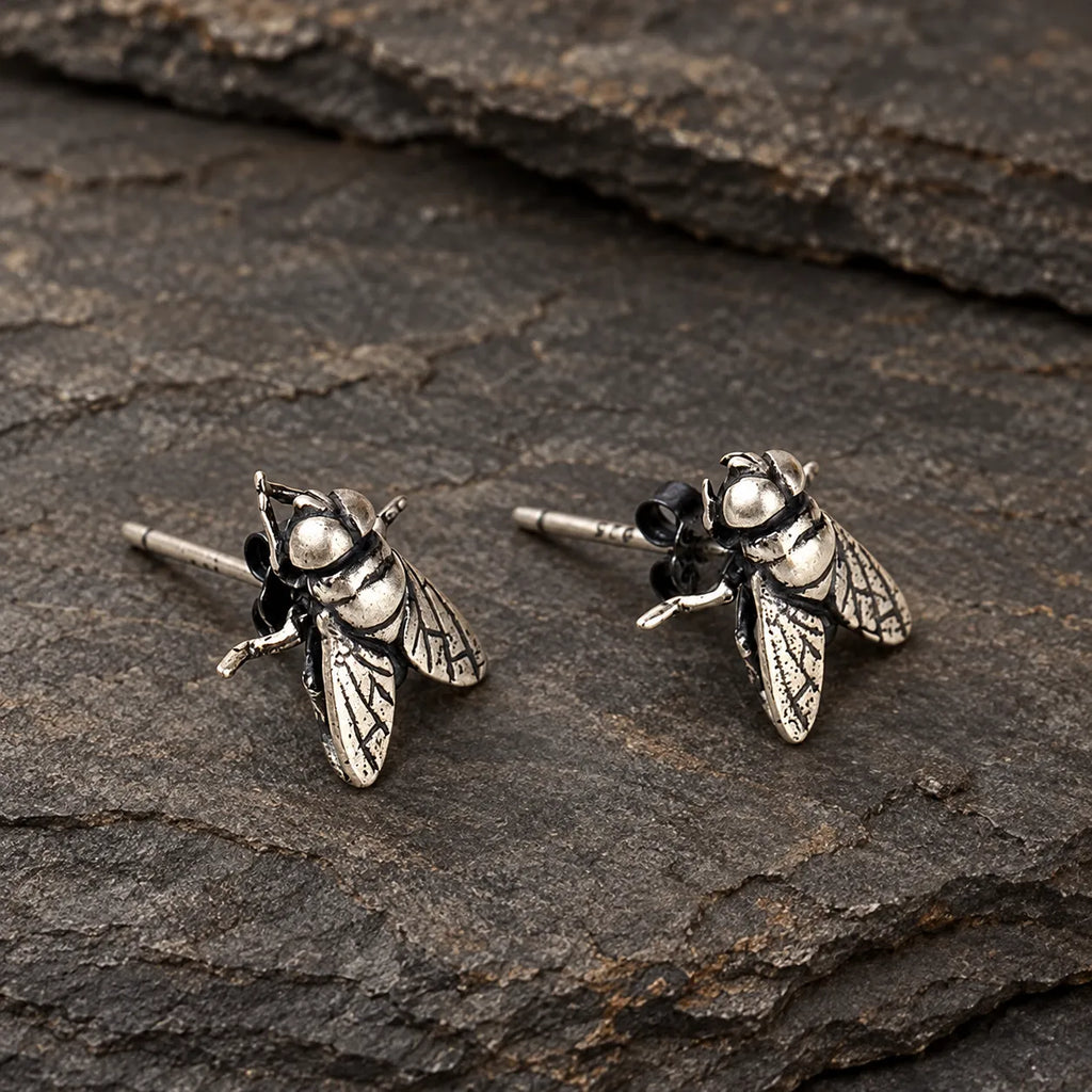 Close view of silver fly earrings showing engraved wing veins and segmented bodies