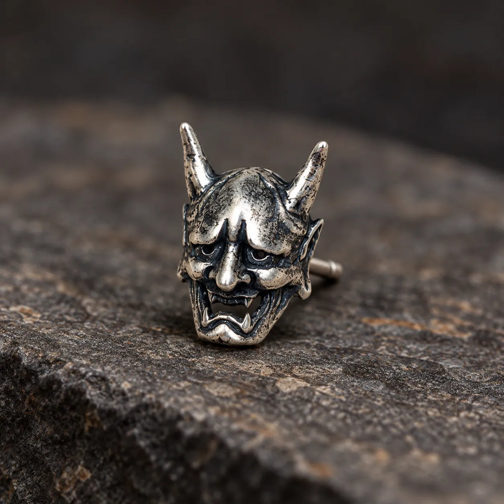 Close view of an oxidized silver Hannya mask stud showing its horns, fangs and sculpted expression