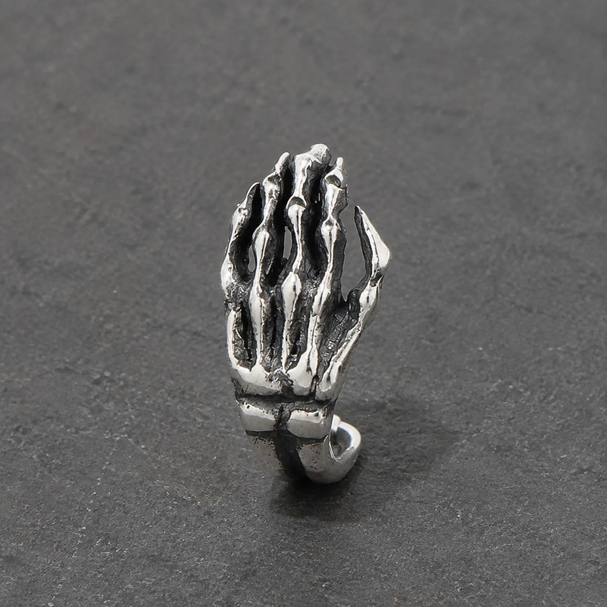Close-up of an oxidized silver skeleton hand stud with sculpted finger bones and dark recesses
