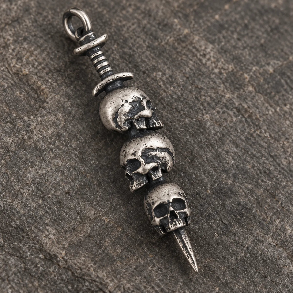 Close-up of the alternating skulls, ribbed dagger hilt and oxidized details of the pendant
