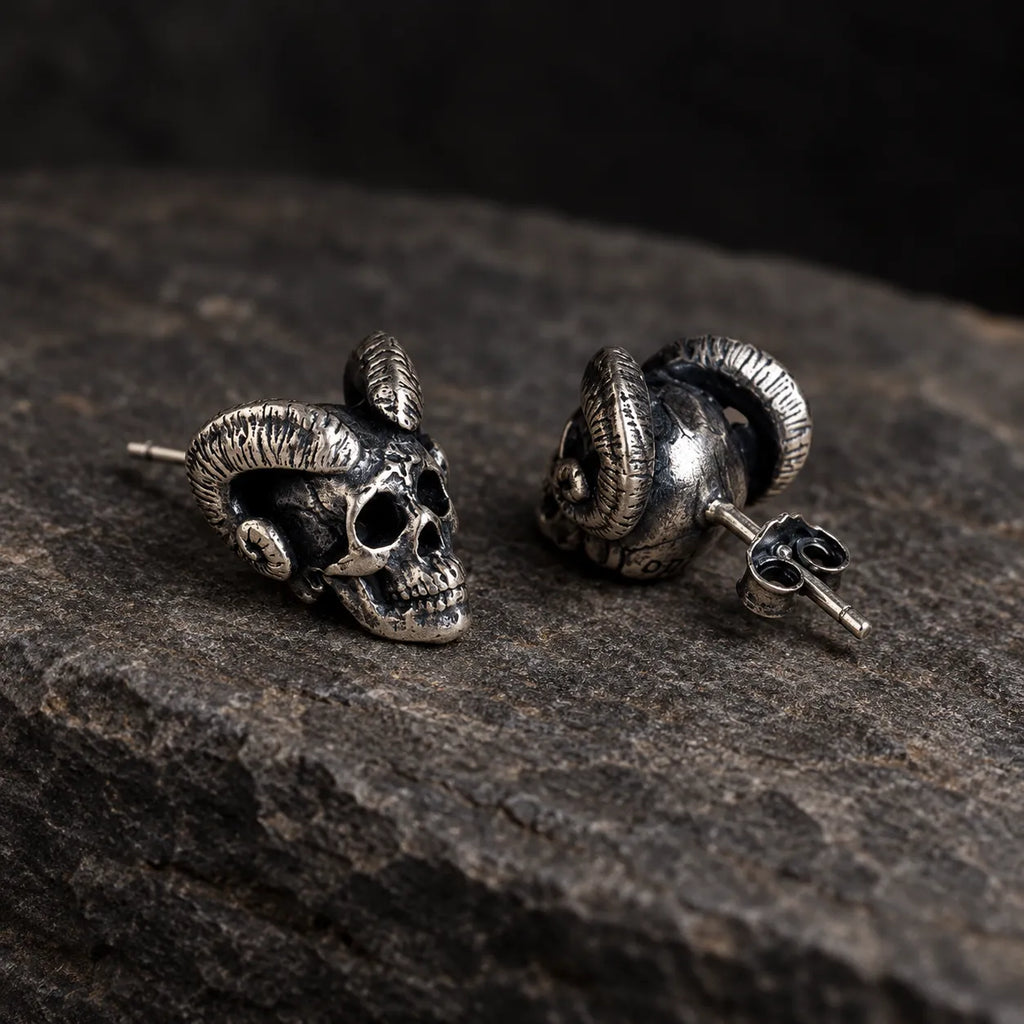 Angled view of ram-horn skull earrings showing their straight posts and butterfly backs