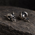 Angled view of ram-horn skull earrings showing their straight posts and butterfly backs