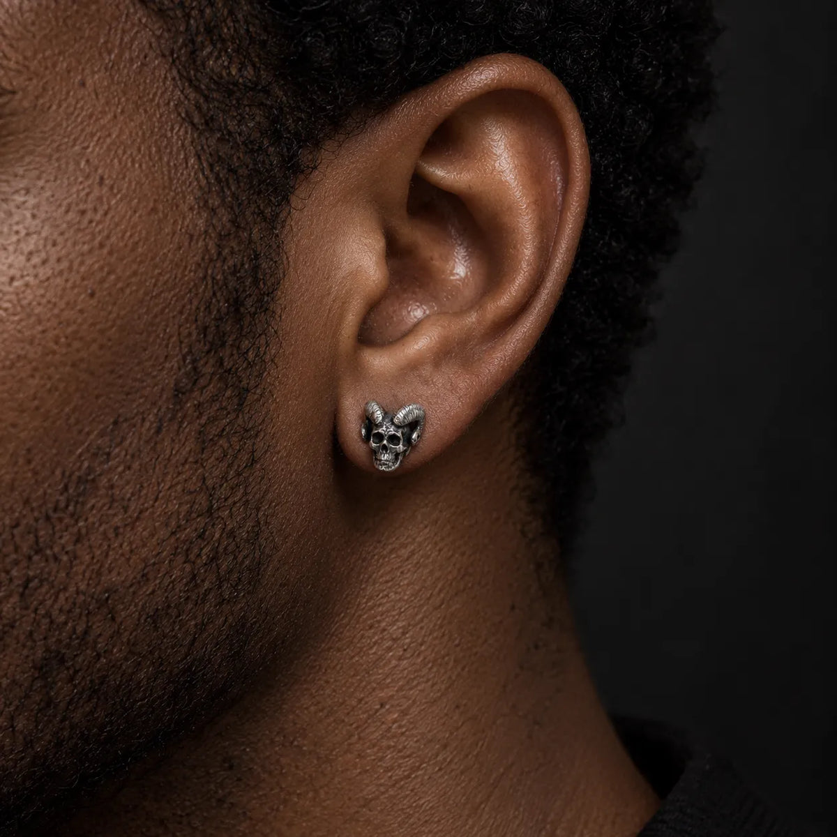 Close-up of a man wearing a ram-horn skull stud earring to show its 11 mm size