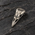Three-quarter view of an oxidized silver raven skull pendant showing its sculptural depth