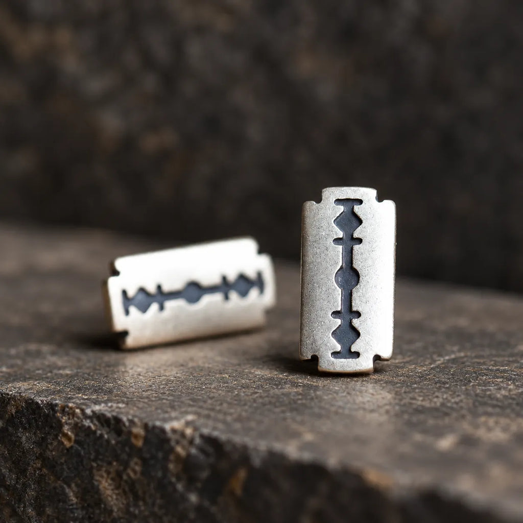 Low-angle view of silver razor blade stud earrings showing their flat construction