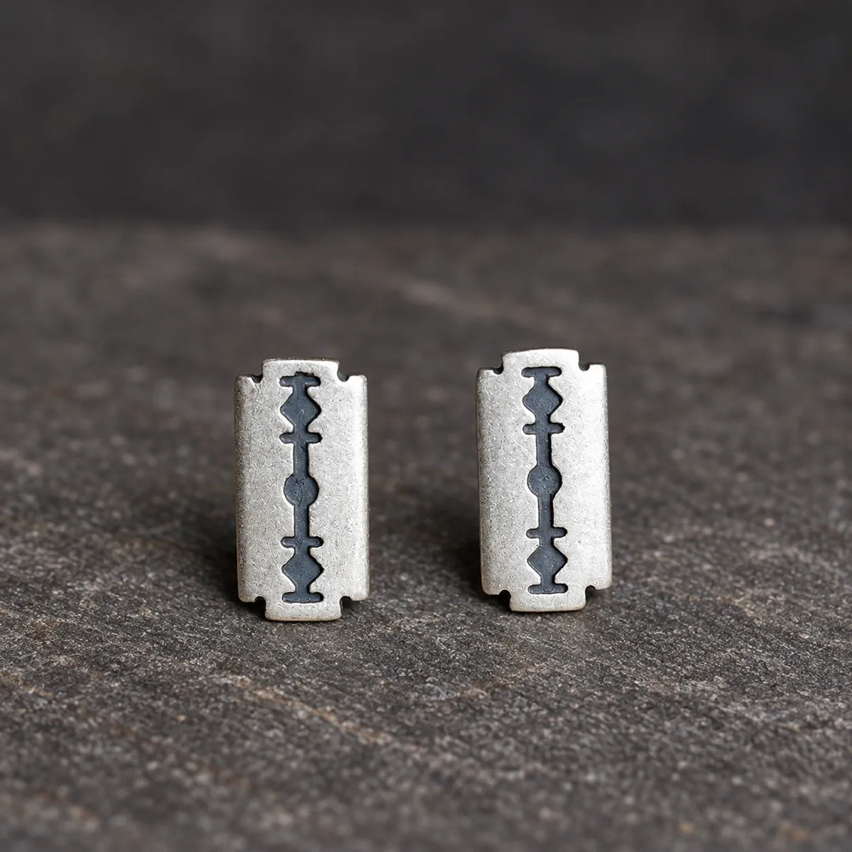 Front view of two oxidized silver razor blade stud earrings positioned vertically