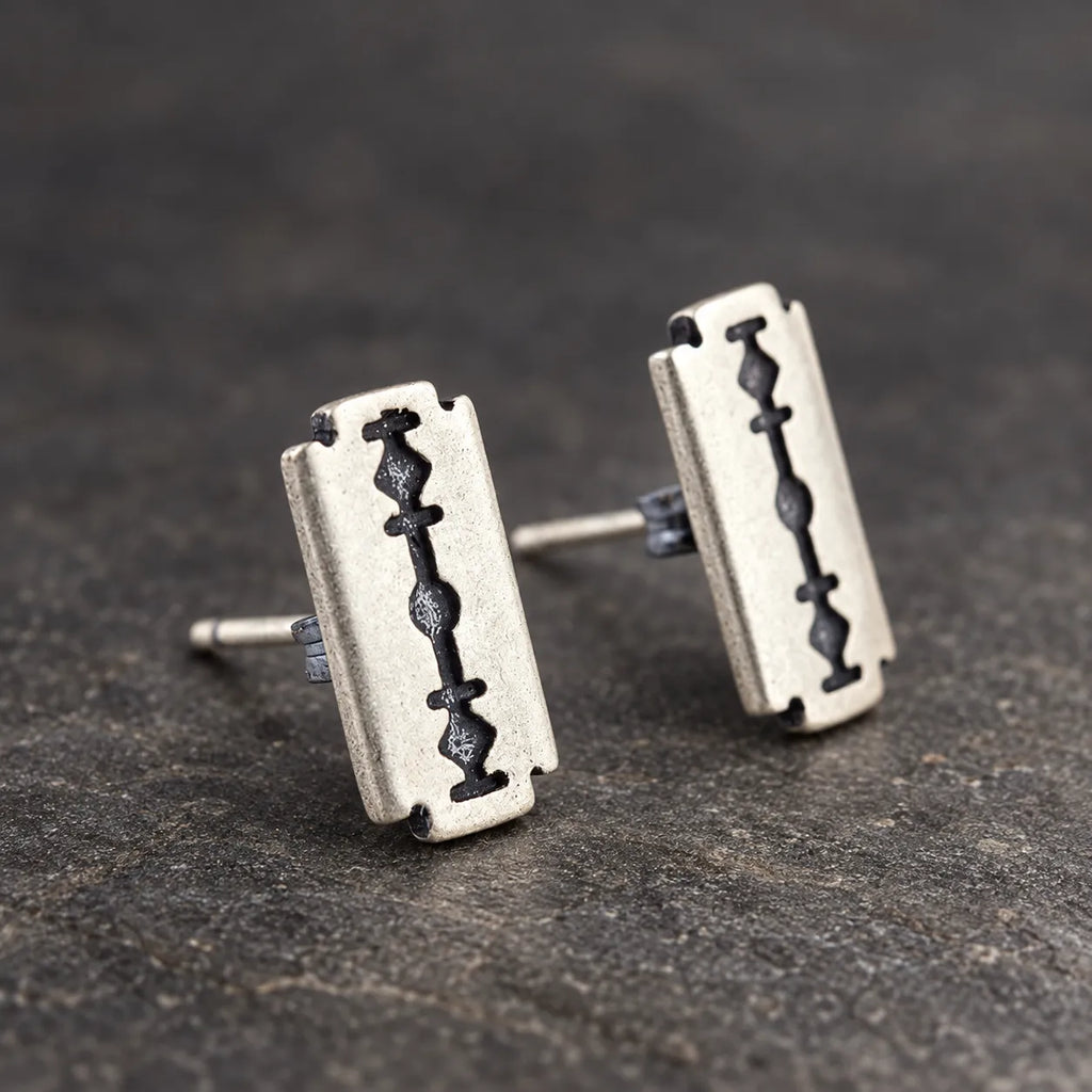 Pair of oxidized sterling silver razor blade stud earrings on dark stone