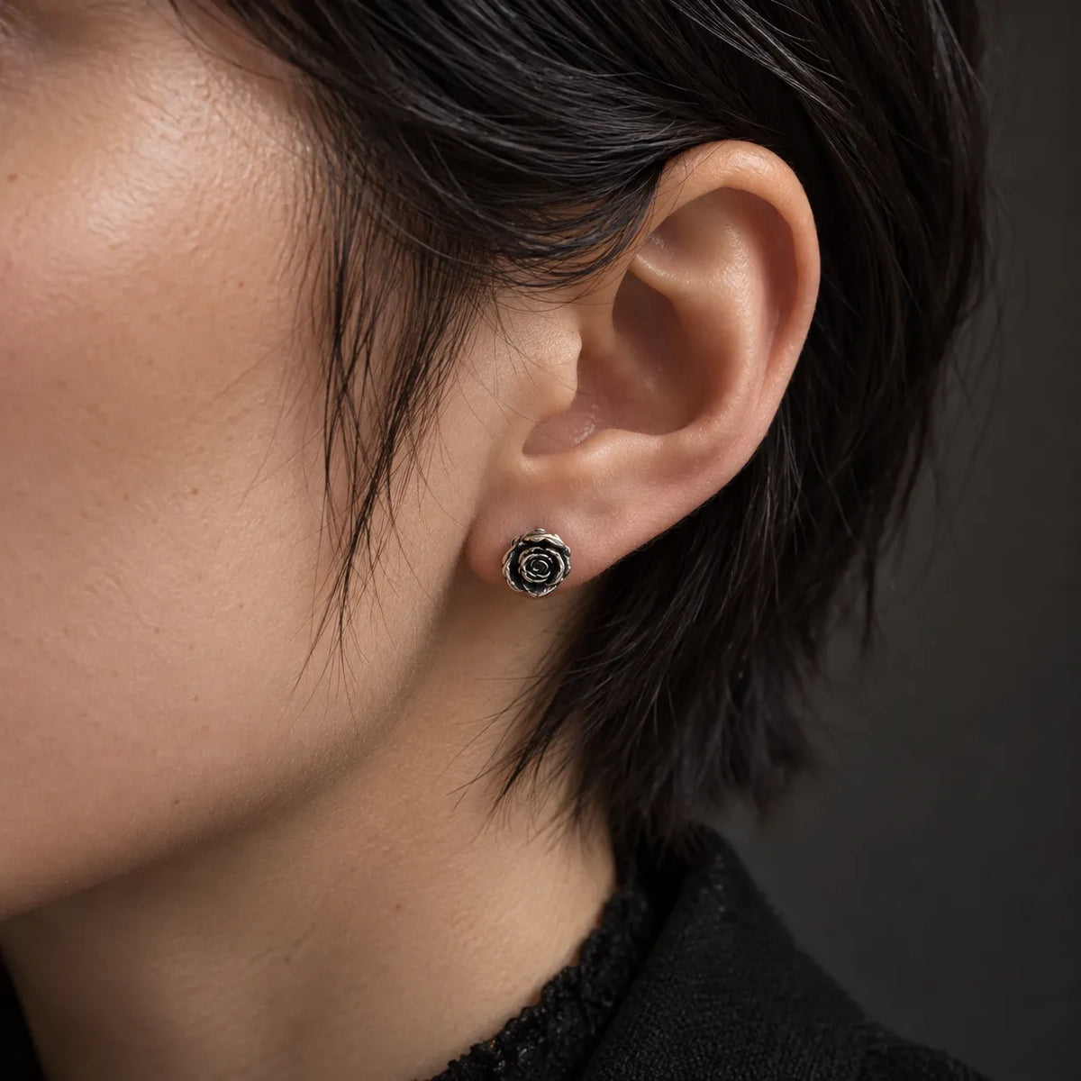 Oxidized silver rose stud earring worn to show its actual 8 by 10 mm size
