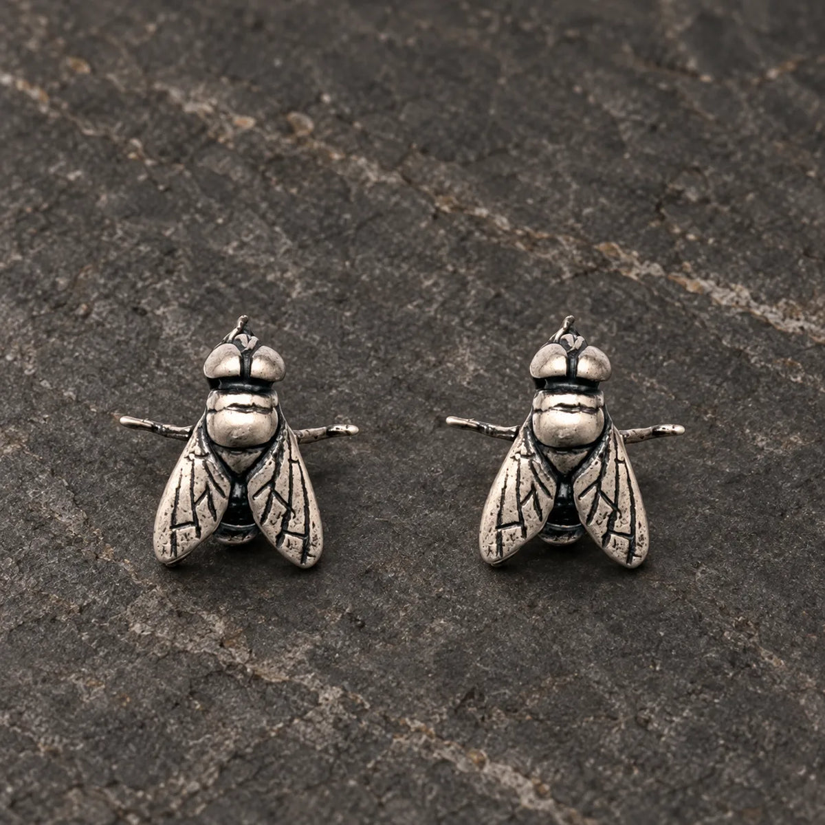Pair of oxidized sterling silver fly stud earrings viewed from the front