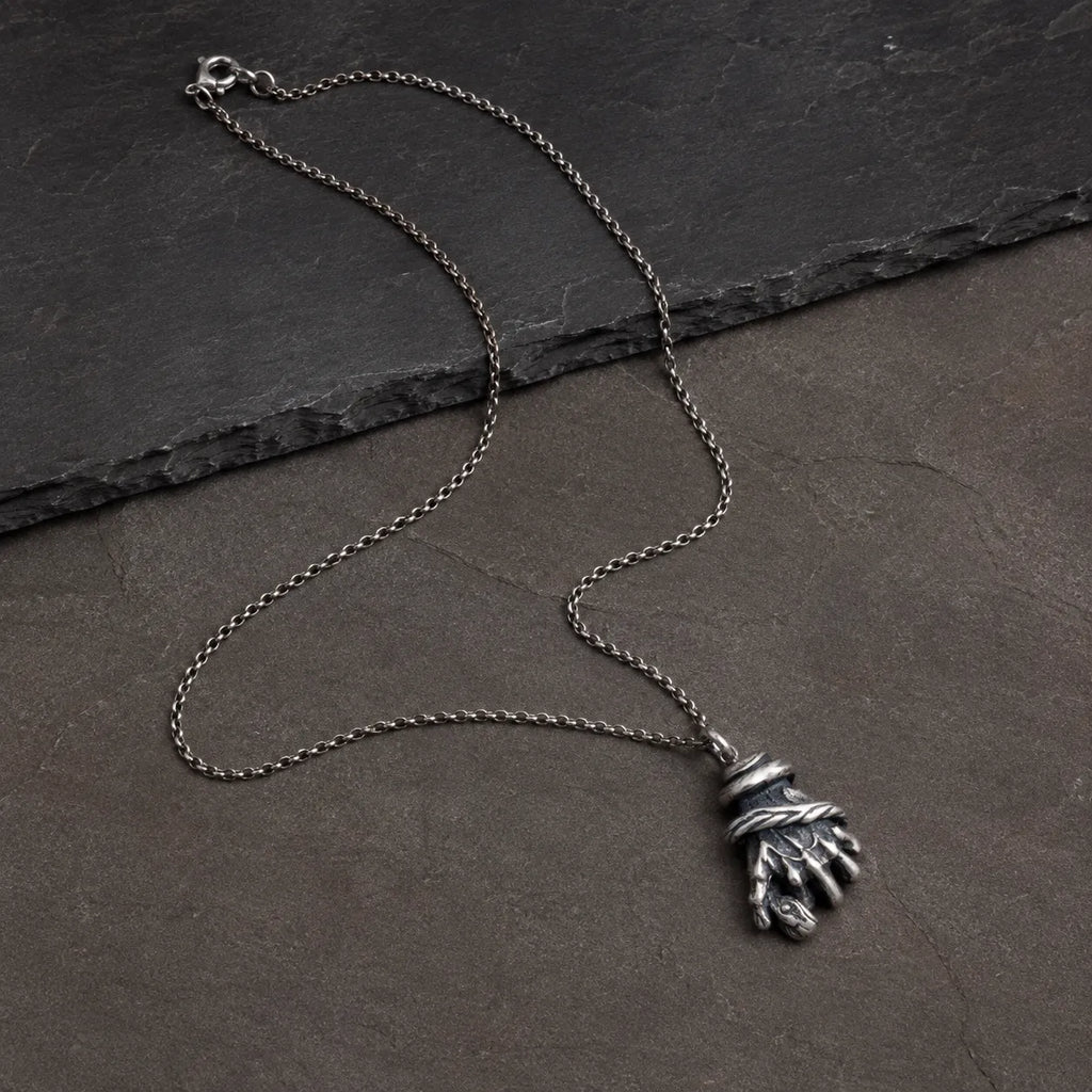 Wide flat lay of the serpent hand pendant with an optional silver chain