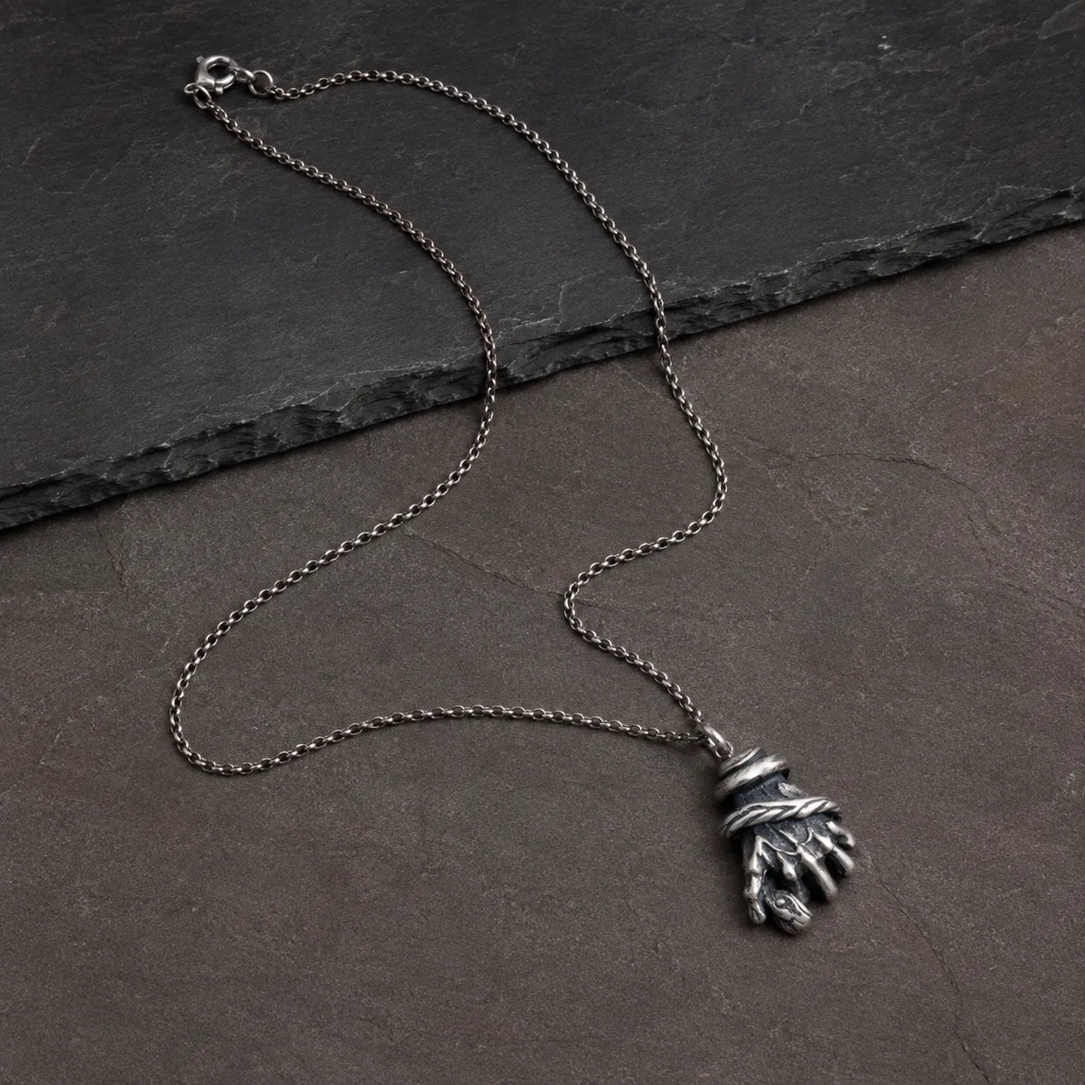 Wide flat lay of the serpent hand pendant with an optional silver chain