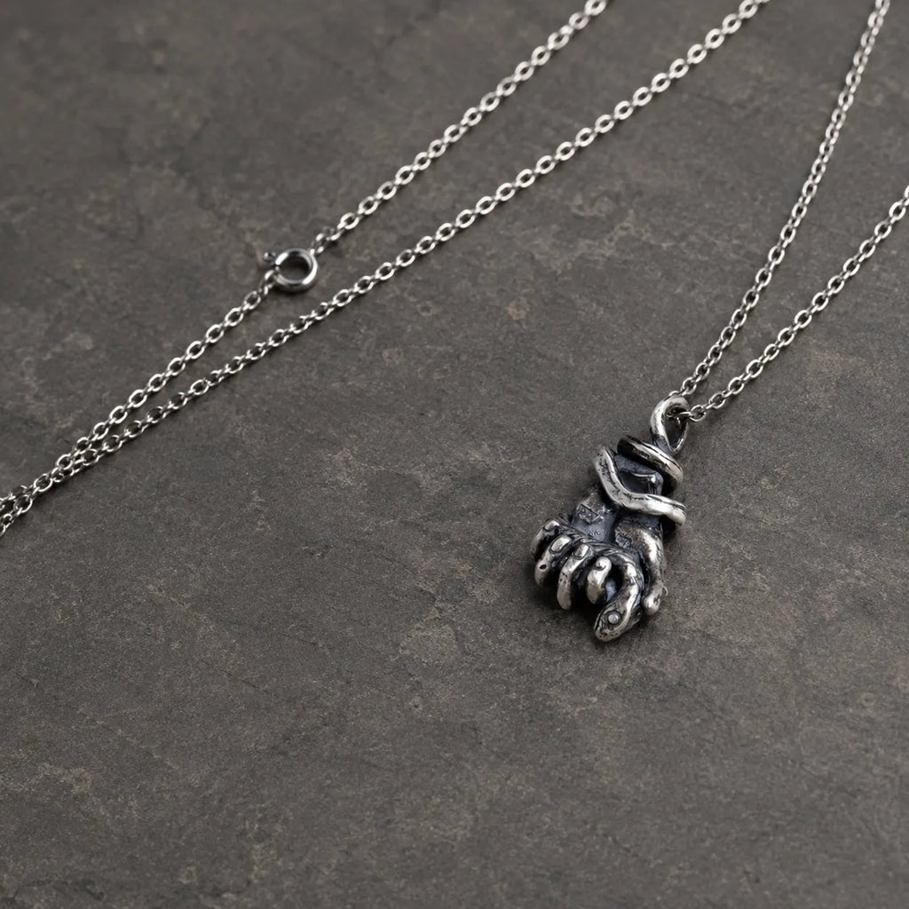 Angled view of the serpent hand pendant showing its curled fingers and fingernails
