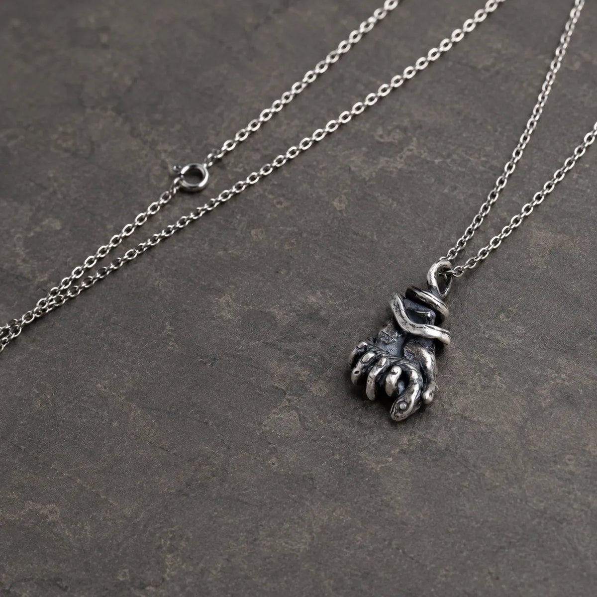 Angled view of the serpent hand pendant showing its curled fingers and fingernails