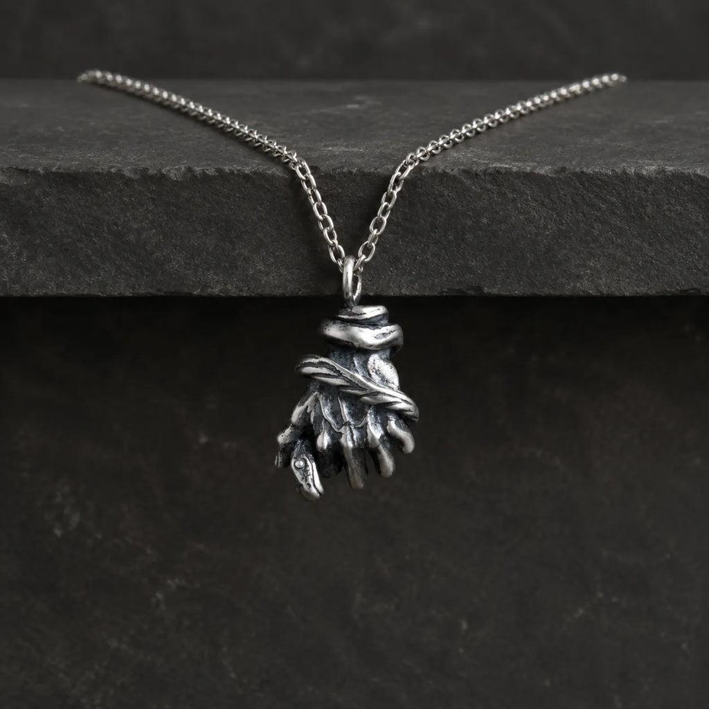 Serpent hand pendant hanging from an optional 2.0 mm chain over dark stone