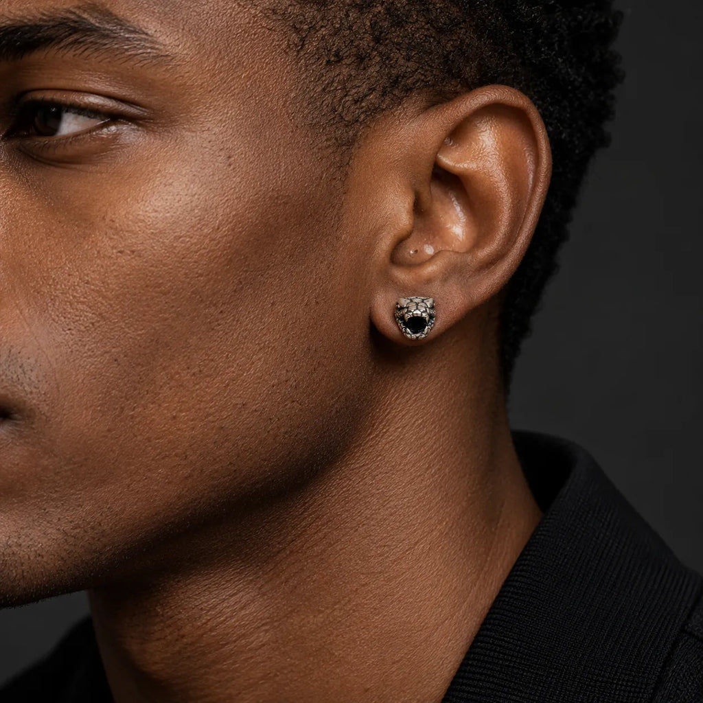 Small serpent head stud earring worn on an ear to show its approximately 5 by 6 mm face size